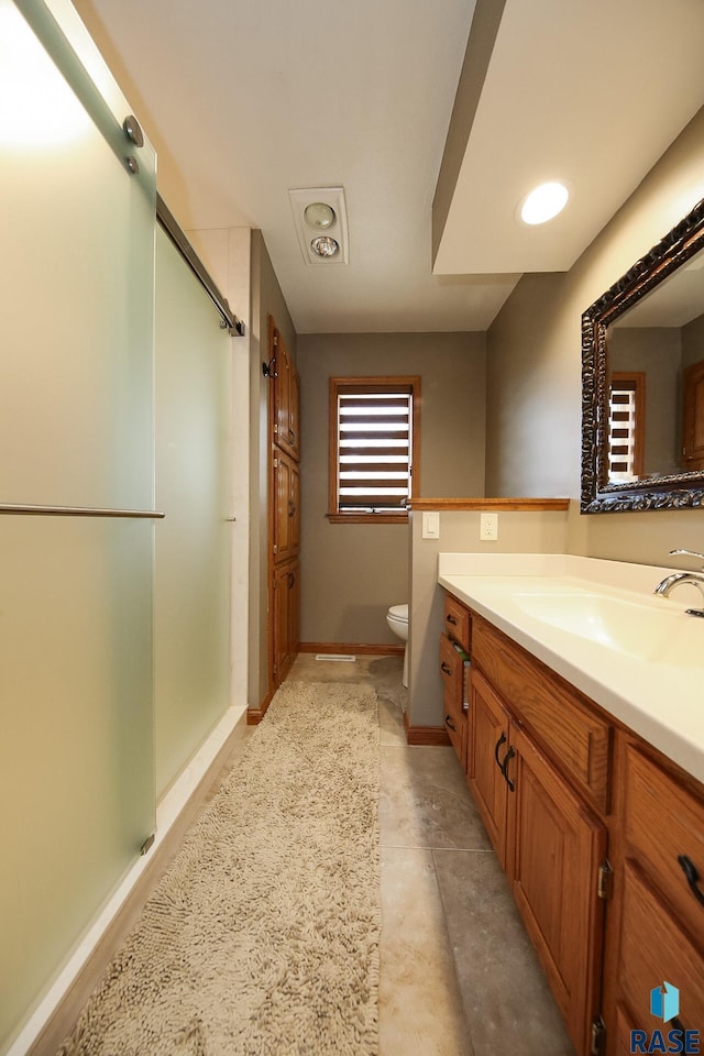 bathroom with a stall shower, toilet, vanity, and baseboards