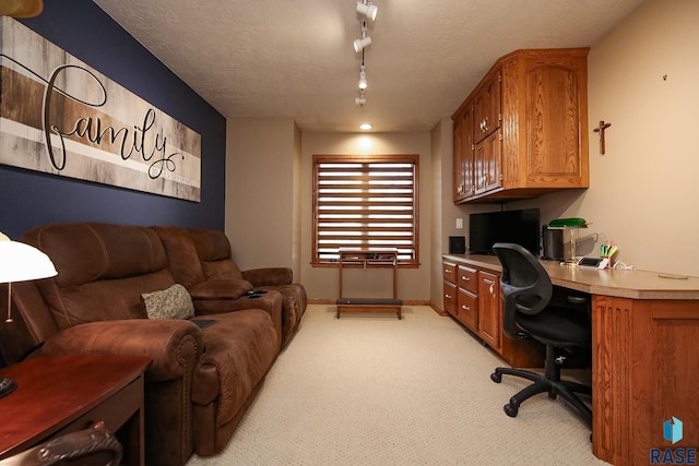 office space featuring a textured ceiling, light carpet, baseboards, and built in study area