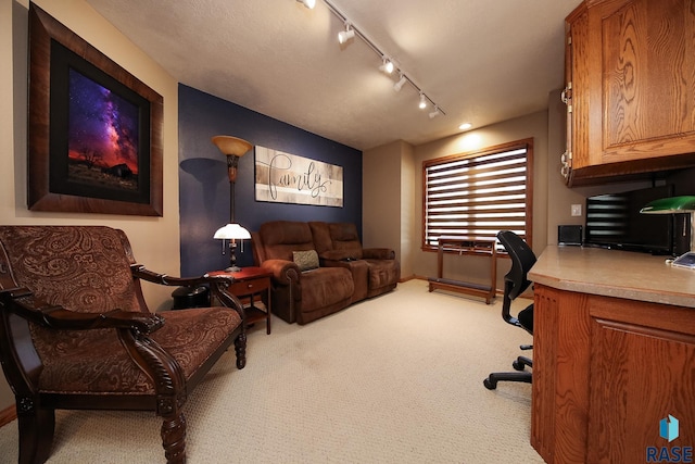 carpeted home office featuring rail lighting and baseboards