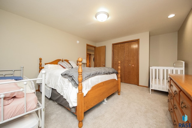 bedroom with a closet, recessed lighting, light carpet, and baseboards