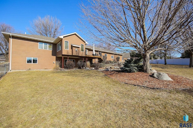 back of house with fence, a lawn, and a wooden deck