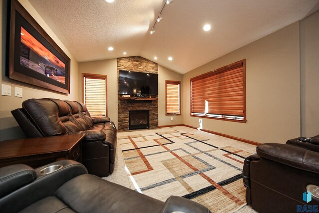 living room featuring baseboards, light colored carpet, vaulted ceiling, a stone fireplace, and a textured ceiling