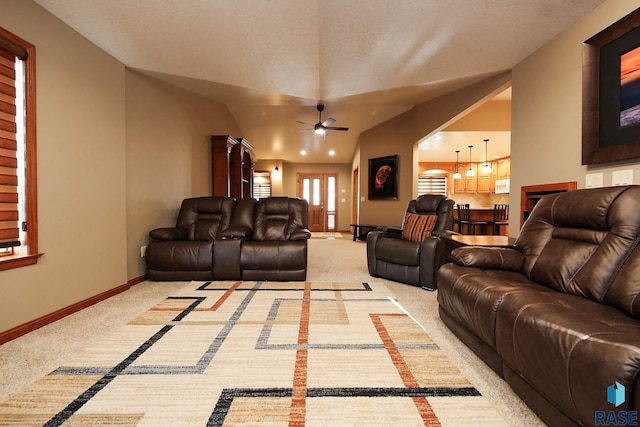 living area featuring a ceiling fan, vaulted ceiling, light colored carpet, and baseboards