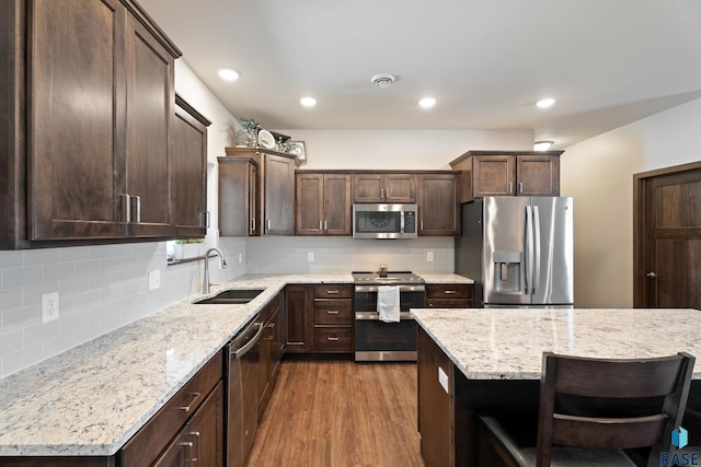 kitchen with dark wood-style floors, a sink, stainless steel appliances, dark brown cabinetry, and tasteful backsplash