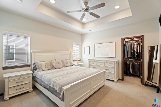 bedroom featuring recessed lighting, a raised ceiling, light colored carpet, and a spacious closet