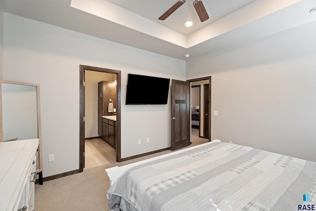 bedroom with a tray ceiling, baseboards, light colored carpet, and a ceiling fan