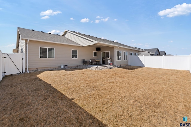 rear view of property with a patio area, a fenced backyard, a yard, and a gate