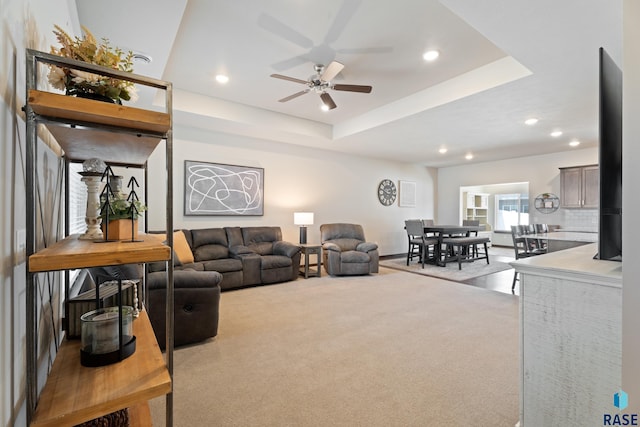 living room featuring a ceiling fan, a raised ceiling, recessed lighting, and carpet floors