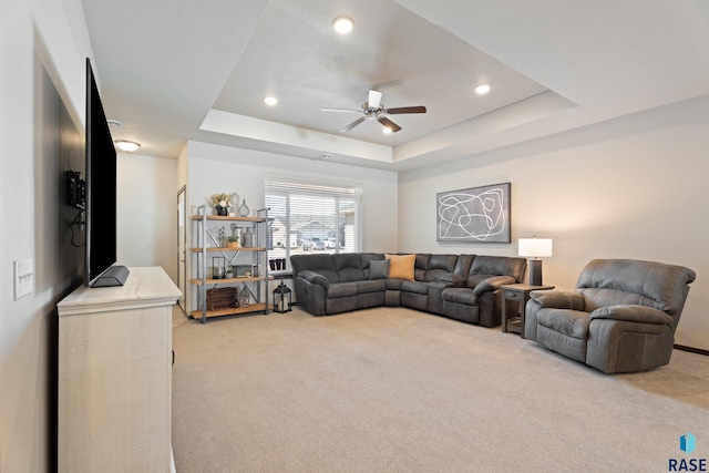 living area featuring recessed lighting, a raised ceiling, light colored carpet, and ceiling fan