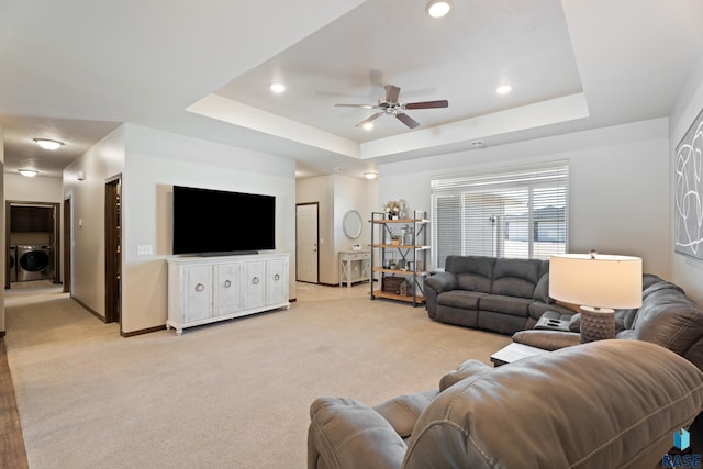 living area with recessed lighting, washer / dryer, light colored carpet, and a raised ceiling