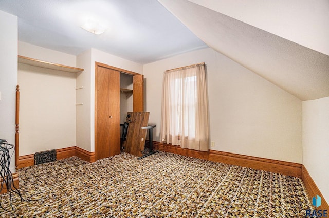 additional living space with baseboards, a textured ceiling, and vaulted ceiling