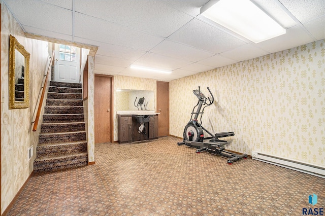 workout room with a drop ceiling, baseboards, baseboard heating, and wallpapered walls