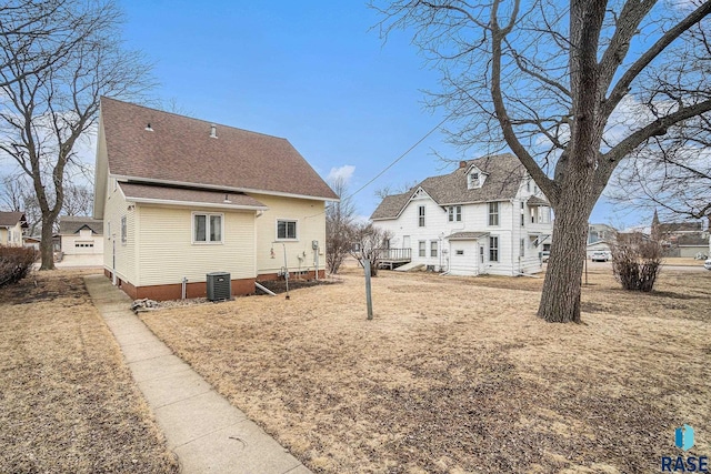 back of property featuring a residential view, roof with shingles, and central AC unit