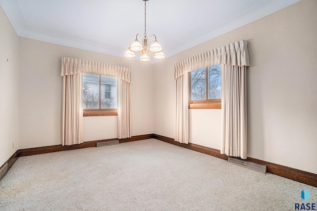 carpeted empty room with visible vents, baseboards, and a chandelier