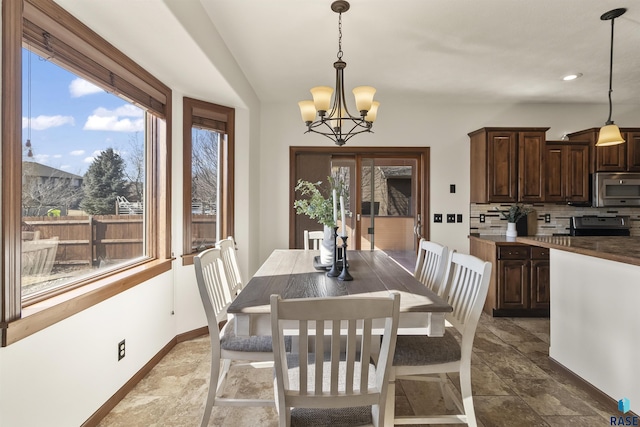 dining room featuring a wealth of natural light, a chandelier, baseboards, and vaulted ceiling