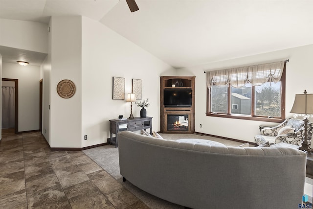 living area featuring baseboards, high vaulted ceiling, a glass covered fireplace, and a ceiling fan