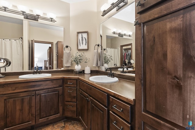 full bath with a sink, stone finish flooring, and double vanity