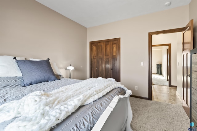 bedroom featuring light tile patterned floors, light colored carpet, a closet, and baseboards