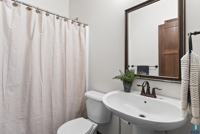 bathroom featuring toilet, a shower with shower curtain, and a sink