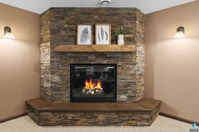 interior details with a stone fireplace, baseboards, and carpet floors