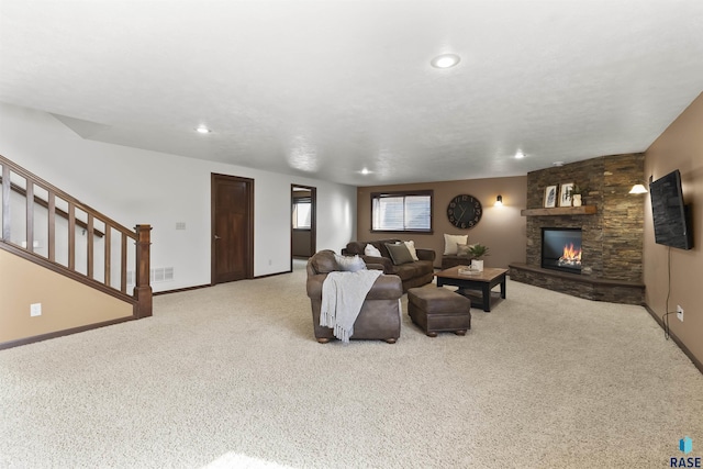 living room with baseboards, visible vents, stairs, a stone fireplace, and light colored carpet