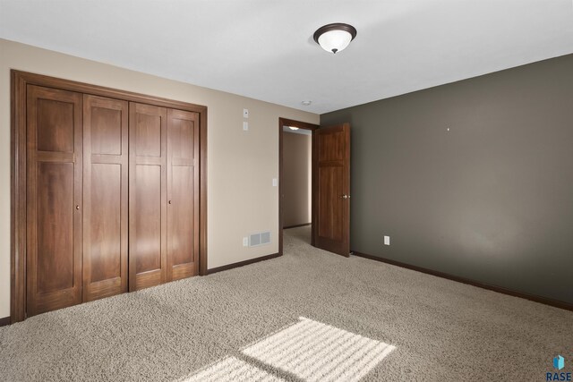 unfurnished bedroom with visible vents, baseboards, a closet, and carpet flooring