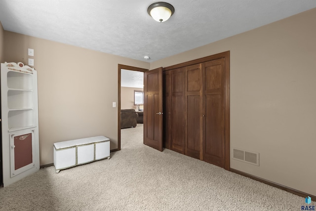 unfurnished bedroom with visible vents, light carpet, a textured ceiling, and baseboards