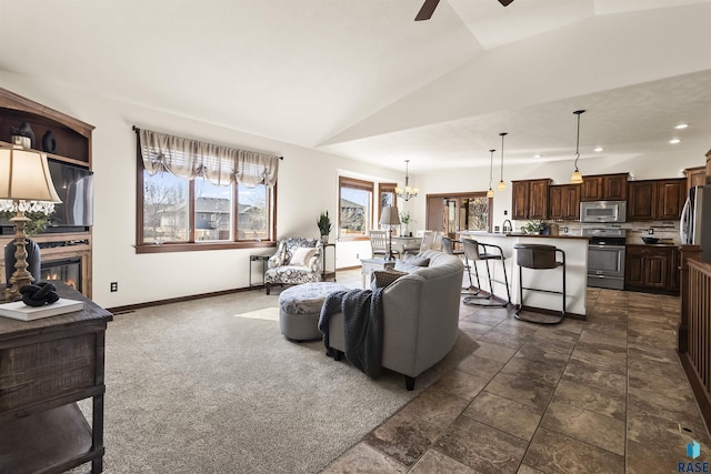 living area with baseboards, lofted ceiling, recessed lighting, ceiling fan with notable chandelier, and a glass covered fireplace