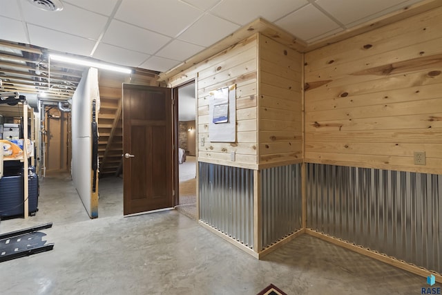 interior space with wooden walls, visible vents, and a drop ceiling