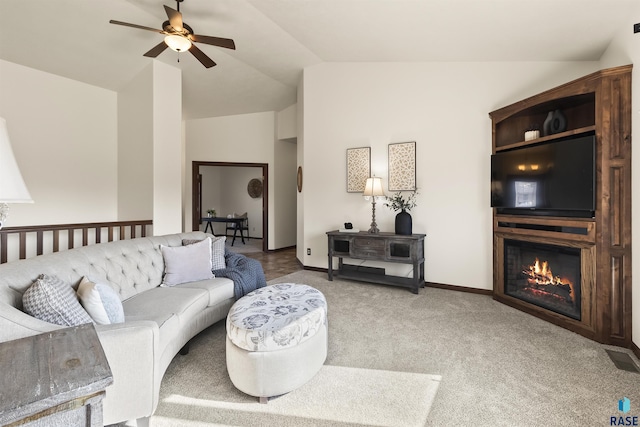 living room featuring lofted ceiling, a glass covered fireplace, carpet flooring, baseboards, and ceiling fan