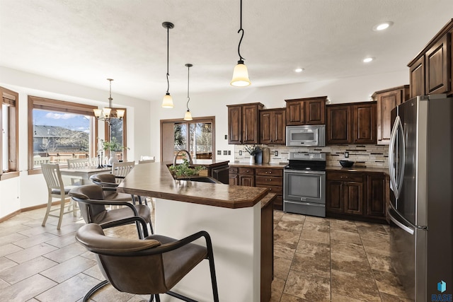 kitchen with a sink, tasteful backsplash, dark countertops, appliances with stainless steel finishes, and dark brown cabinets