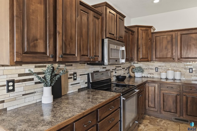 kitchen featuring visible vents, stainless steel appliances, dark brown cabinetry, dark countertops, and tasteful backsplash