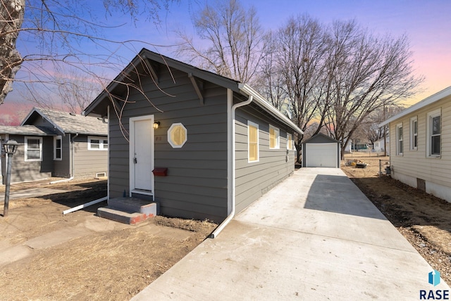 bungalow-style home with an outbuilding, entry steps, concrete driveway, and a detached garage