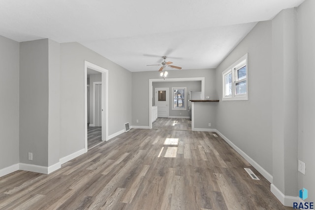 unfurnished living room featuring a ceiling fan, wood finished floors, visible vents, and baseboards