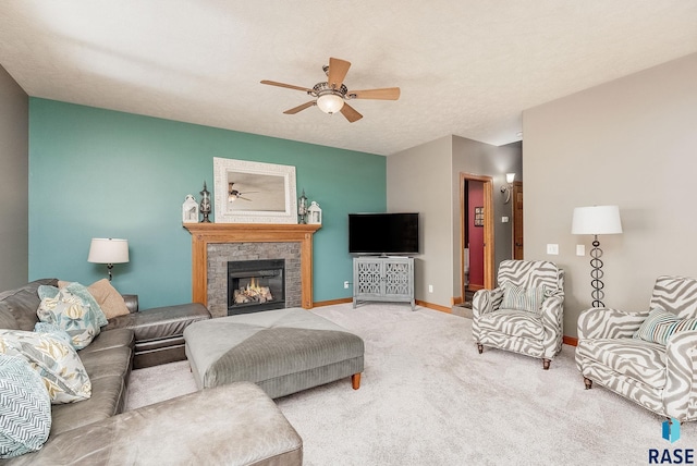 living area featuring ceiling fan, baseboards, a lit fireplace, carpet flooring, and a textured ceiling