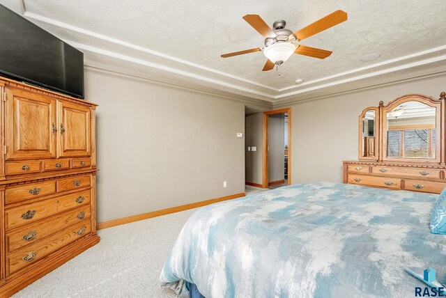 bedroom featuring baseboards, ornamental molding, light carpet, a textured ceiling, and a raised ceiling