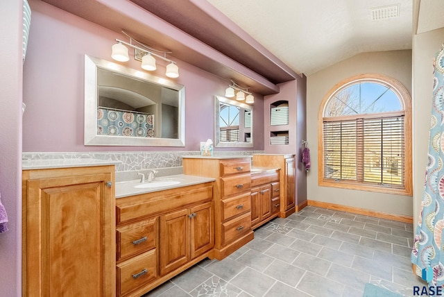 bathroom featuring a wealth of natural light, visible vents, vanity, and vaulted ceiling