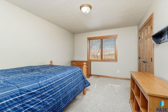 bedroom with light carpet, a textured ceiling, and baseboards