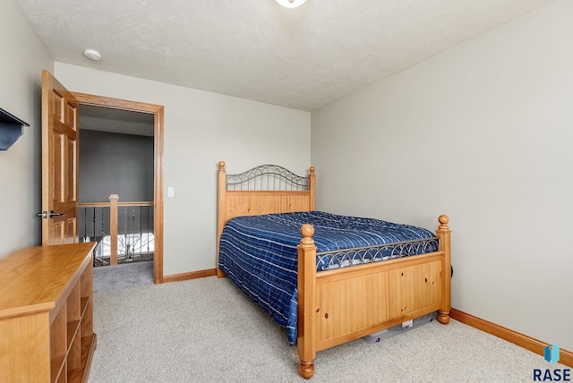 bedroom featuring light colored carpet, a textured ceiling, and baseboards