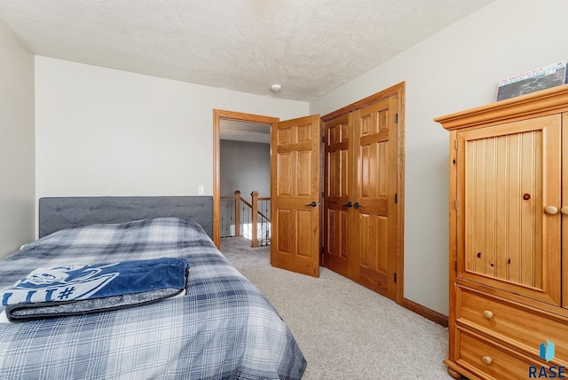 bedroom with a textured ceiling, baseboards, and light carpet