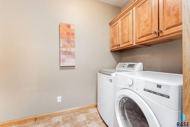 laundry area featuring stone finish floor, cabinet space, independent washer and dryer, and baseboards