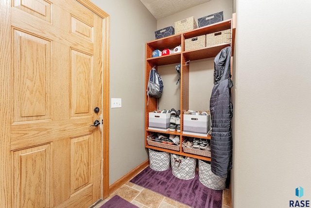 mudroom featuring stone finish flooring and baseboards