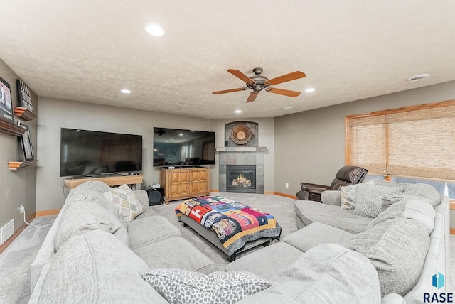 living area with a tiled fireplace, a textured ceiling, recessed lighting, carpet floors, and baseboards