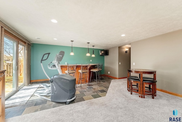 interior space with a textured ceiling, baseboards, recessed lighting, stone finish flooring, and a dry bar