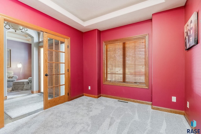 carpeted spare room featuring visible vents, baseboards, and french doors