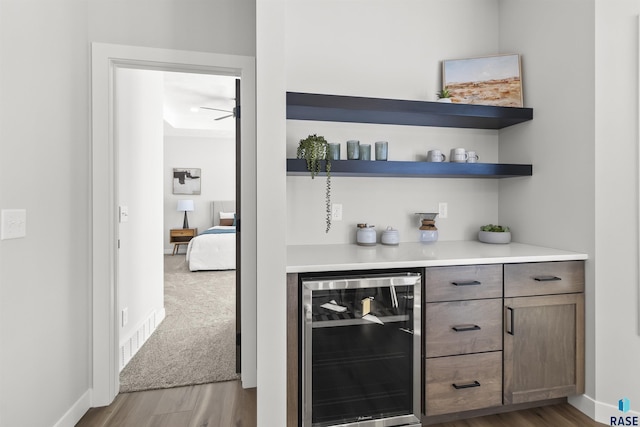 bar featuring baseboards, wood finished floors, visible vents, and beverage cooler