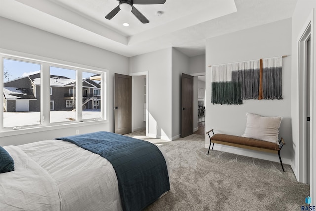 bedroom featuring ceiling fan, baseboards, a tray ceiling, and carpet floors