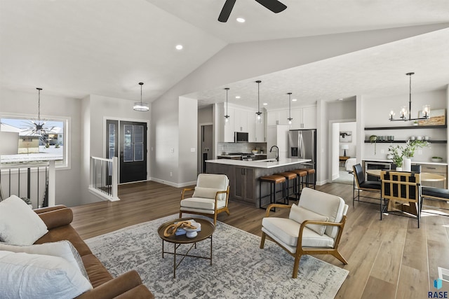 living area with recessed lighting, baseboards, light wood-style floors, and ceiling fan with notable chandelier