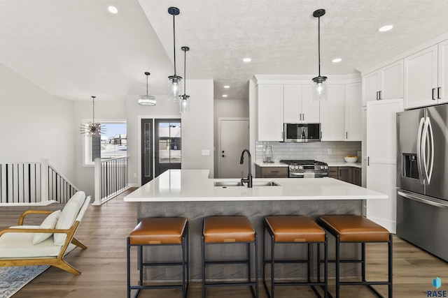 kitchen featuring backsplash, a breakfast bar area, appliances with stainless steel finishes, dark wood-style floors, and a sink