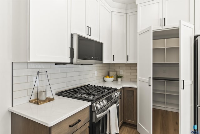 kitchen with white cabinetry, backsplash, and appliances with stainless steel finishes